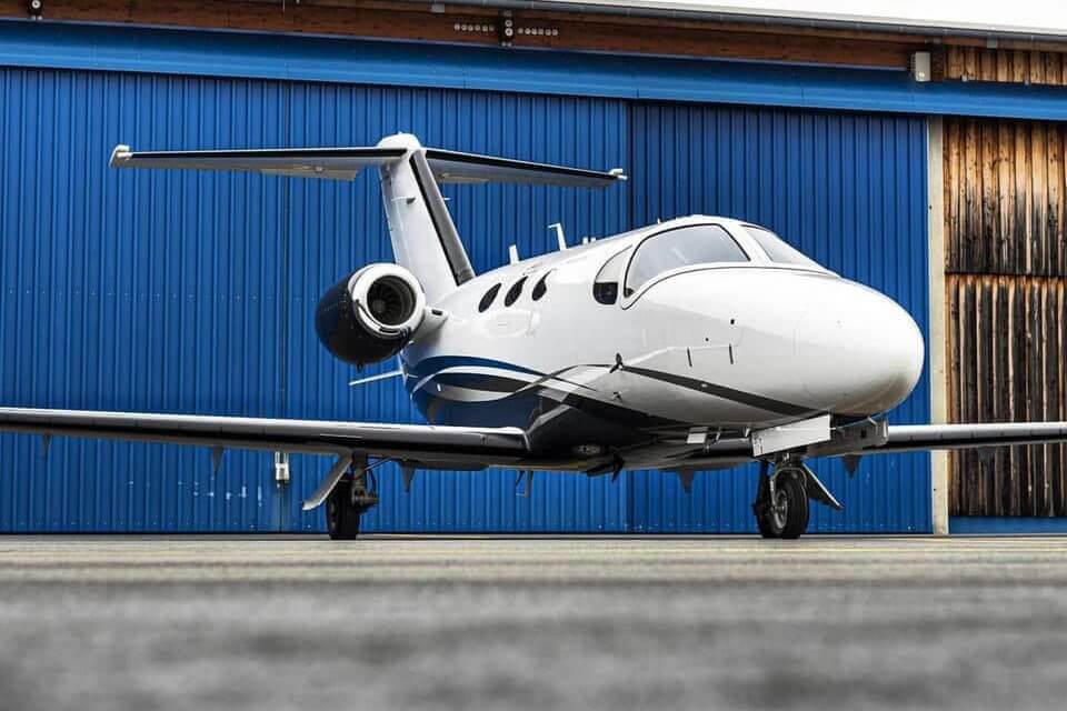 Cessna Citation Mustang parked on the apron outside a hangar
